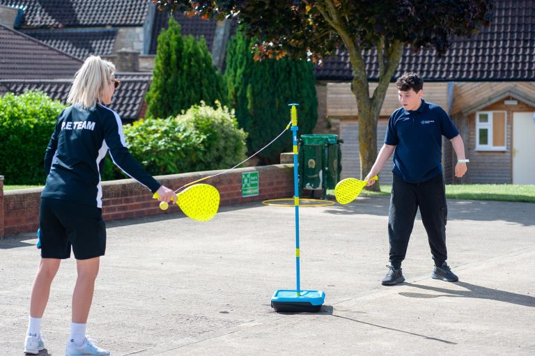 A pupil plays swingball with a teacher