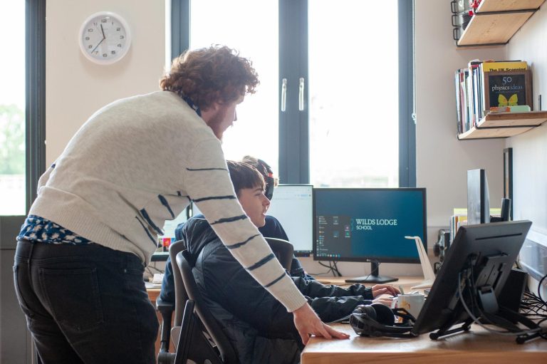 A teacher supervises puplils on computers