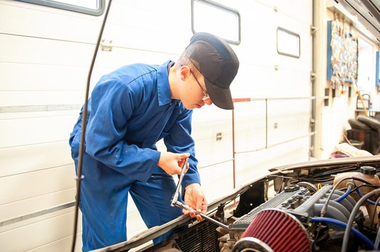 A teenage mechanic works on a car engine