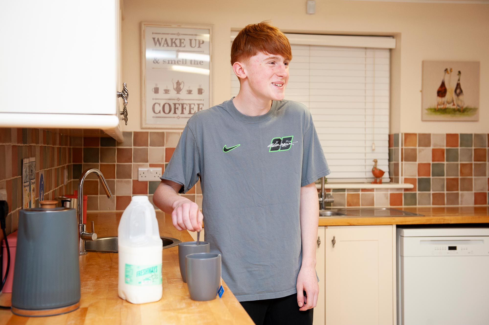 A pupil makes a cup of tea in a boarding hosue kitchen