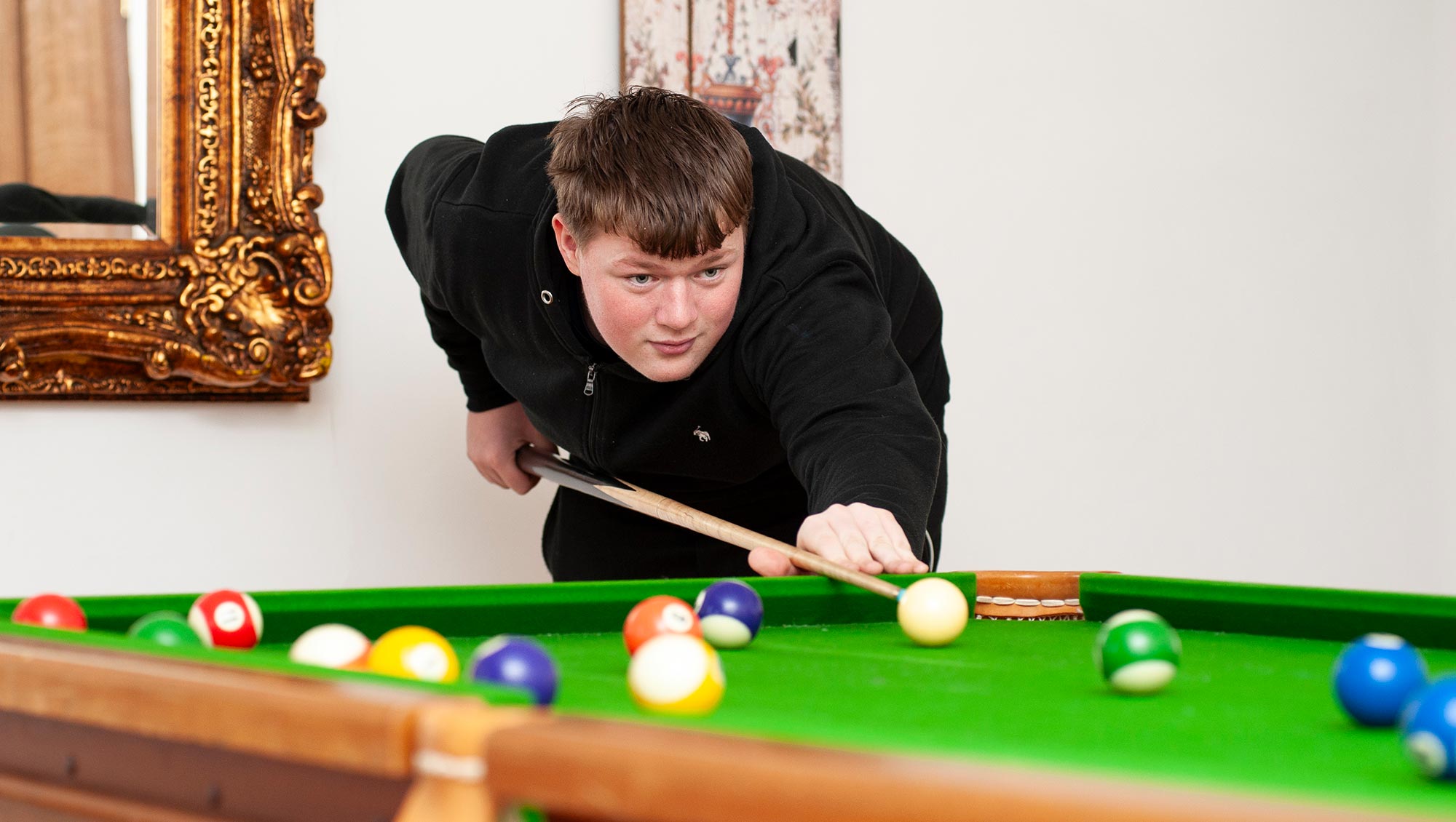A pupil plays pool in a boarding house