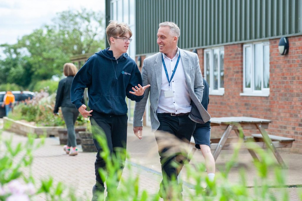 A headmaster walks with a pupil