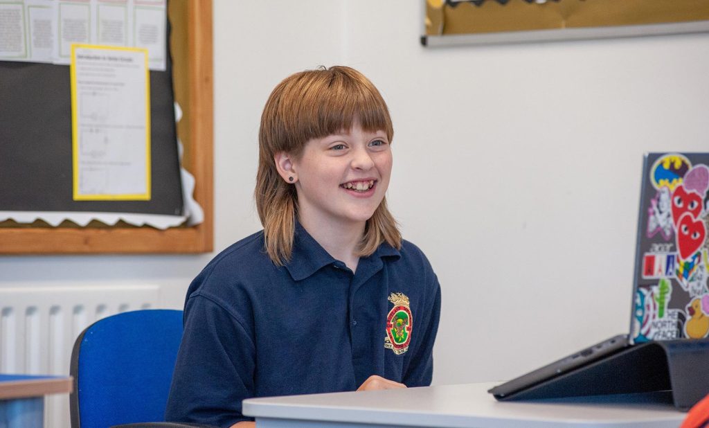 A smiling pupil at a laptop